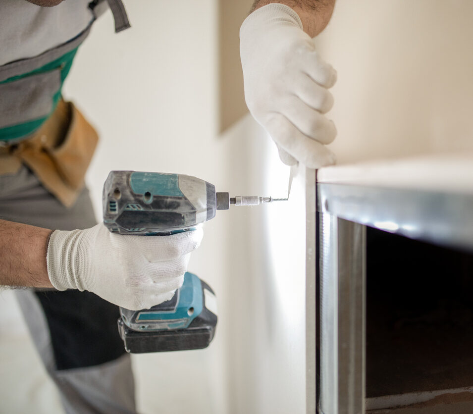 Ein Handwerker verschraubt eine Gipskartonplatte mit einer Wandkonstruktion aus Metall