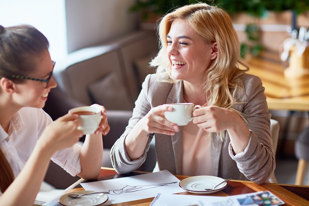 Zwei lachende Frauen trinken Kaffee im Café